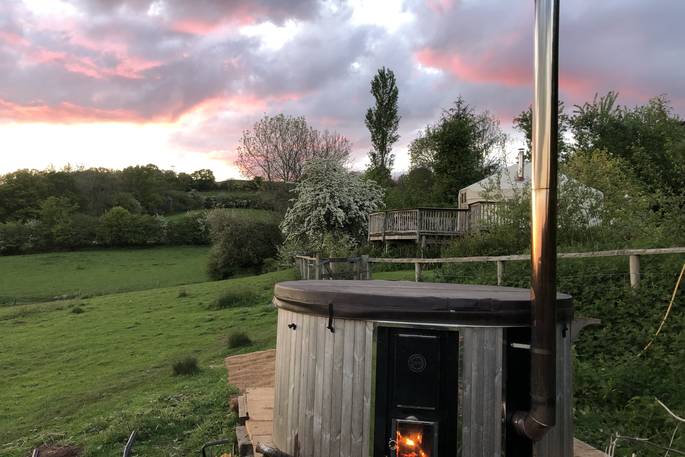Sit in the wood-fired hot tub and watch the sunset at Secret Garden Yurt in Monmouthshire