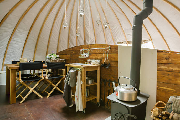 Kitchen and dining area with logburner and kettle at Catta Dee, Penhein Glamping in Monmouthshire