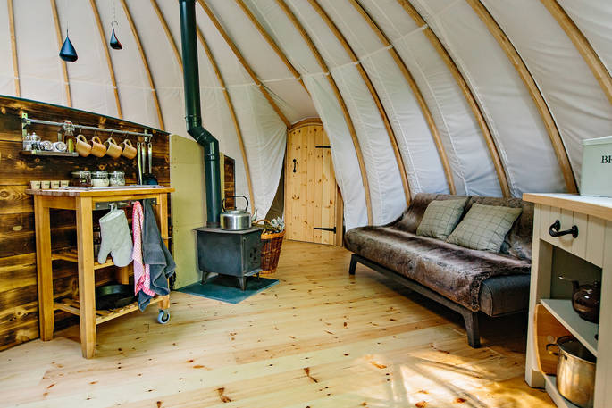 Cosy logburner, sofa bed and kitchen area at The Coombe tent, Penhein Glamping in Monmouthshire