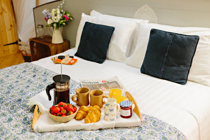 Delicious breakfast is served on the kingsize bed at The Coombe tent, Penhein Glamping