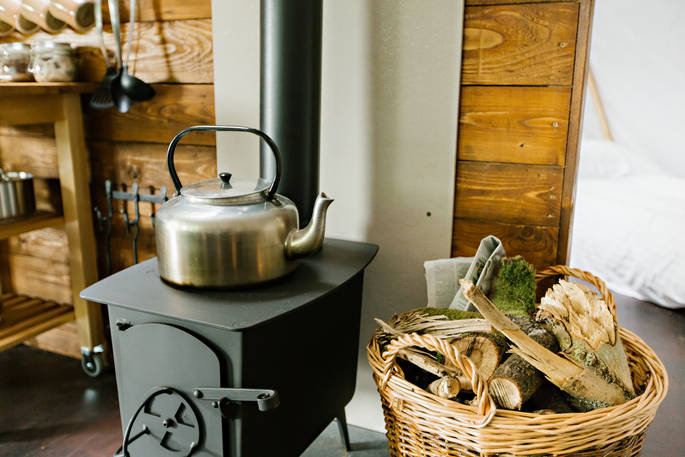 Kettle and log burner inside The Cribbau tent at Penhein Glamping in Monmouthshire