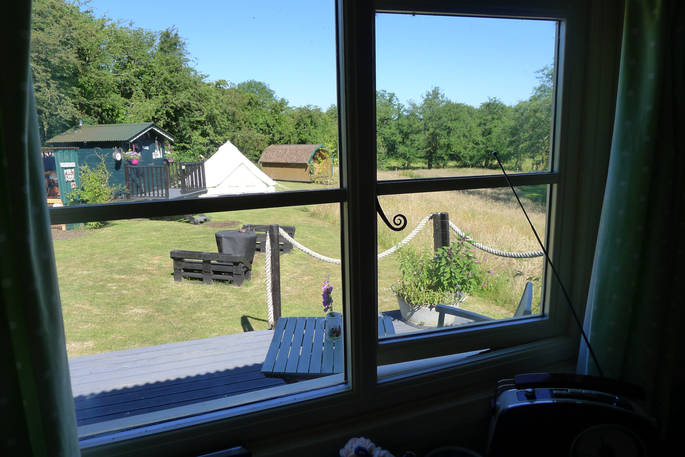 View of Cwt Gwyrdd camp seen through the window inside the shepherd's hut