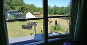 View of Cwt Gwyrdd camp seen through the window inside the shepherd's hut