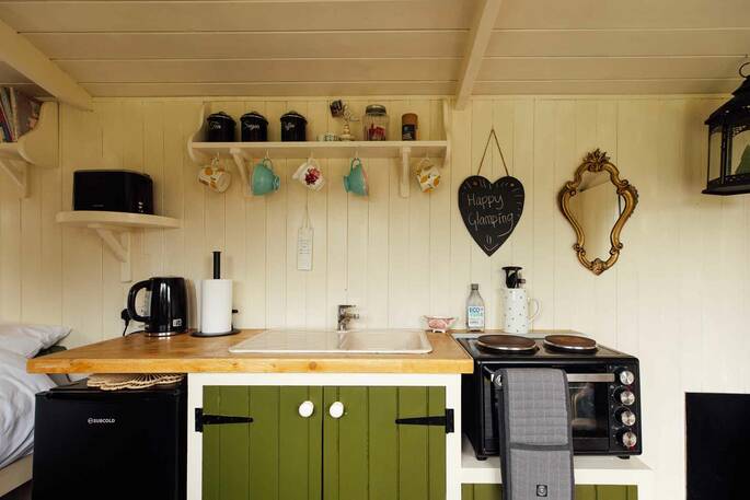 Kitchen equipped with a microwave oven and hob, undercounter fridge and cooking utensils