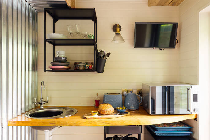 Kitchenette with a microwave, sink, cooking utensils, crockery and glassware
