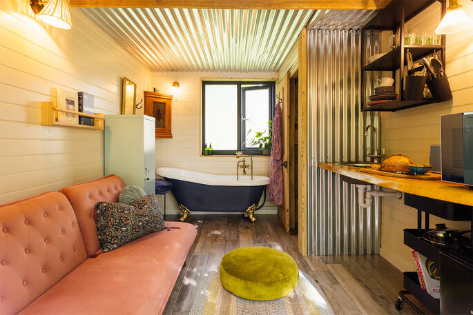 Interior has a kitchenette, sofa bed and a roll top bath tub next to the bathroom
