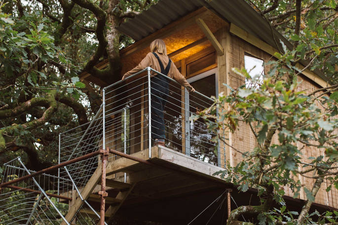 An exterior view of the Beudy Banc Treehouse with balcony, in Powys, Wales