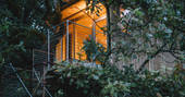 Beudy Banc treehouse lit up at dusk in Powys, Wales