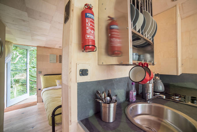 Fully equipped kitchen with bedroom behind inside of Beudy Banc treehouse in Powys 