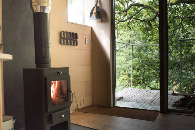 Light the wood-burner inside Beudy Banc Treehouse in Powys 