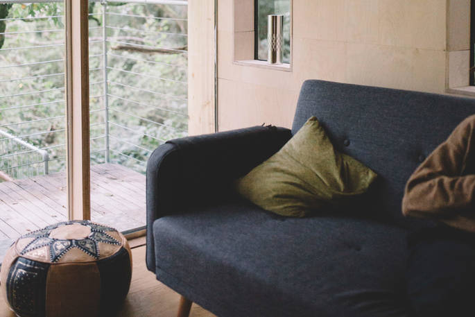 The cosy living space with views of the trees at Beudy Banc treehouse in Powys, Wales