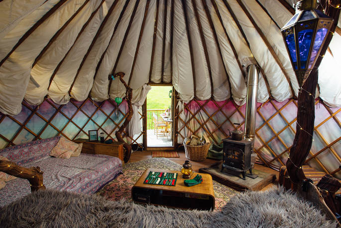 The cosy interior of Jericho yurt equipped with log burner, comfy areas to lounge and a table to play cards in Powys, Wales.