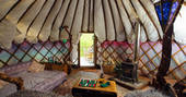 The cosy interior of Jericho yurt equipped with log burner, comfy areas to lounge and a table to play cards in Powys, Wales.