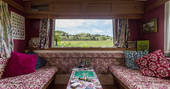 Seating area inside Van Goff cabin at Bodynfoel Hall. Enjoy a glass of wine and game of scrabble with views of the local countryside and neighbouring sheep