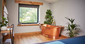 Copper bath tub in the main bedroom at The Burrow in Powys