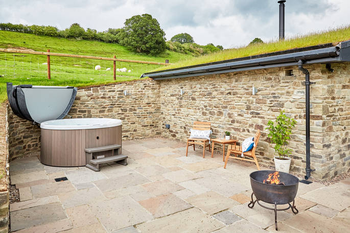 Hot tub and fire pit in the outdoor space next to The Burrow at Dolassey Farm in Powys