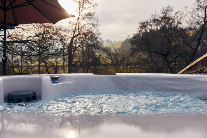 Relax in the hot tub with views of the woods all around at The Burrow in Powys, Wales
