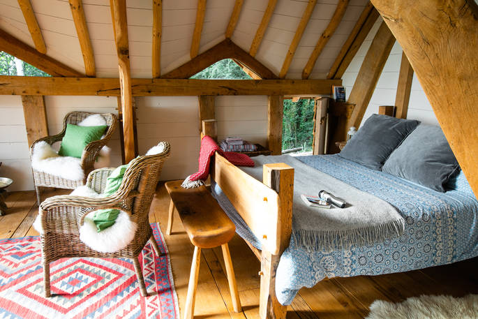 Comfortable kingsize bed and beautifully quirky furnishings inside Dragon's Cruck cabin at Sunnylea