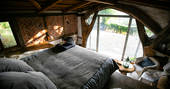 The huge comfortable bed inside The Sleepout, with views of the Powys countryside through the window