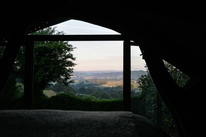 View from the bed at The Sleepout during sunrise, with breathtaking views of the Powys countryside