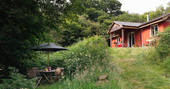 An external view of The Straw Cottage and the hidden woodland dining area in Powys, Wales