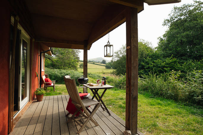 Sit on the covered decking and admire views of the valleys and mountains at The Straw Cottage in Powys, Wales