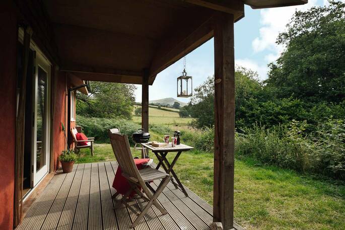 Sit on the covered decking and admire views of the valleys and mountains at The Straw Cottage in Powys, Wales