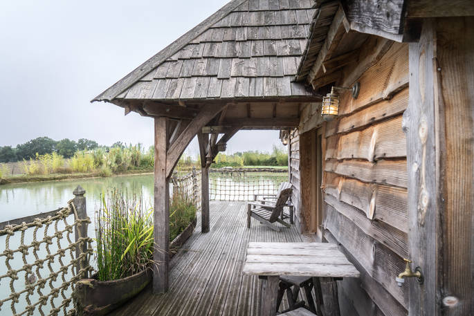 Relax on the terrace and enjoy the view across the lake at Chateau Biron, Châteaux dans les Arbres, Dordogne, France