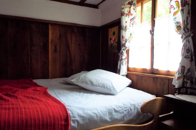 Comfortable double bed in Fisherman's cabin, with wooden panelling and a window with cosy curtains at Fisherman's Cabin, France