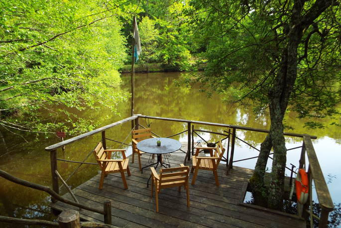 Comfortable wooden al fresco dining area overlooking the tranquil lake at Fisherman's Cabin in France.