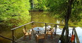 Comfortable wooden al fresco dining area overlooking the tranquil lake at Fisherman's Cabin in France.