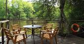Comfortable al fresco dining area outside on the wooden patio overlooking the water at Covert Cabin, France