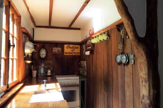 Cosy wooden panelled fully-equipped kitchen at the Fisherman's cabin in the Dordogne. On the wall hang decorations, utensils, and mugs, France