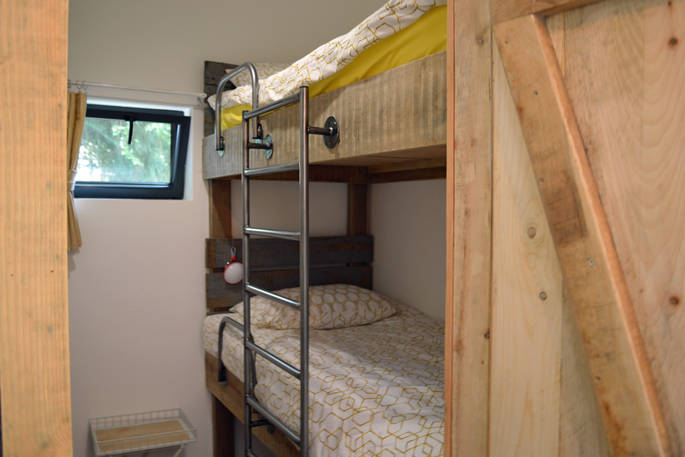 Bunk beds that have bespoke industrial style metal ladders and handrails inside of GoGreen cabin