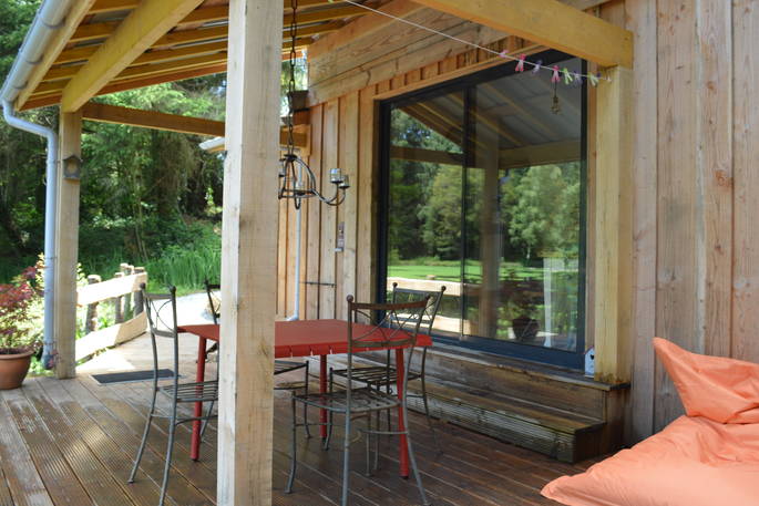 Large decking with patio doors and table outside of GoGreen Cabin at Dordogne in France