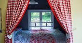 Cosy double bed with chic bedding and window looking out on the forest 