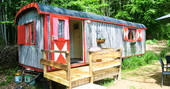 An external view of GoGreen Roulette shepherd's hut with cute curtains and a decking space in Dordogne, France