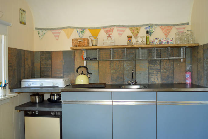 Kitchen area inside of GoGreen Roulotte with quirky shelf and bunting 