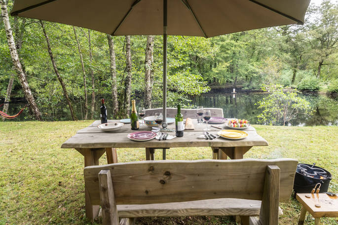 A grand table for dining by the lake at Poacher's Cabin in Dordogne, France
