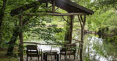 The covered seating area overlooking the lake at Poacher's Cabin in Dordogne, France