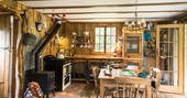 The fully equipped kitchen with dining table and wood burner at Poacher's Cabin in Dordogne, France