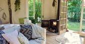 An interior view of Elvensong in Dordogne with a cosy sofa, blankets and wood burner