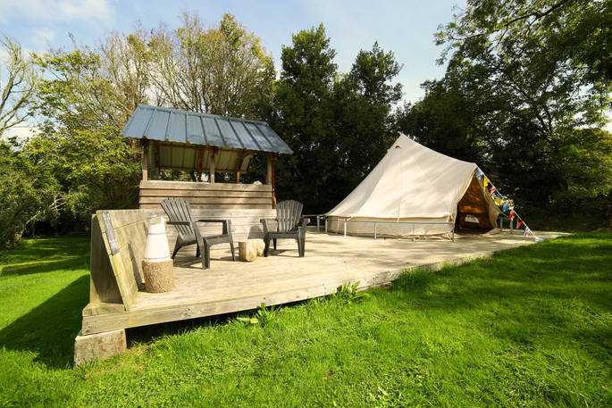 Sit outside on the wooden decking outside of Atoll bell tent at Bot-Conan Lodge in France