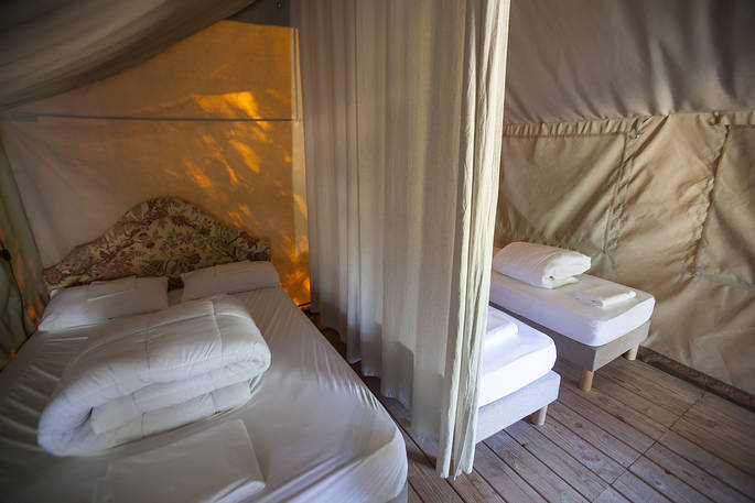One double bed and two single beds divided by a curtain inside of Bananec Lodge Tent at Bot-Conan Lodge