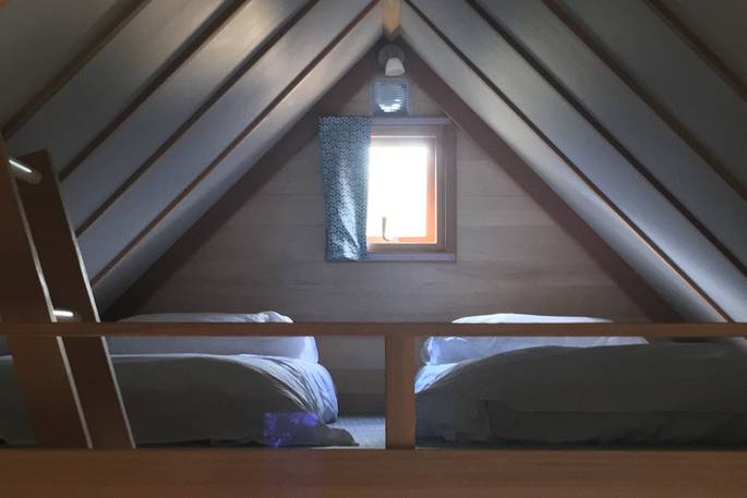 Two single beds on the mezzanine level inside the cabin at Bot-Conan in France