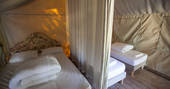 One double bed and two single beds divided by a curtain inside of Penfret Lodge Tent at Bot-Conan Lodge