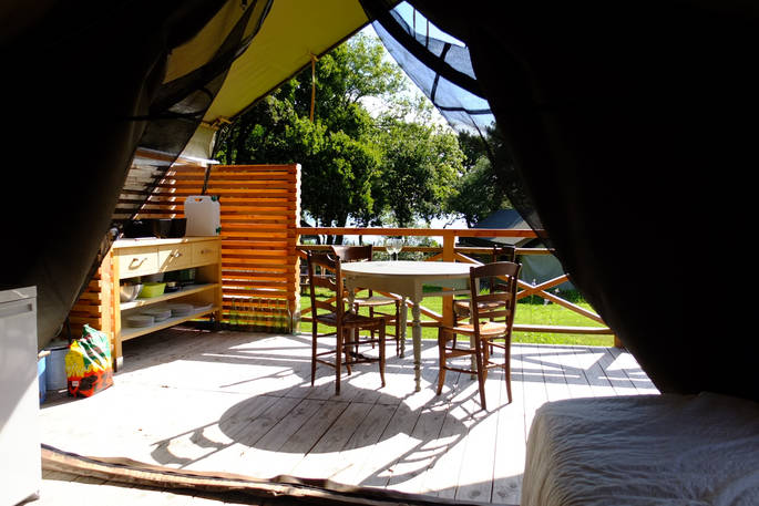 Outdoor dining table and kitchen area in the sun outside of Penfret lodge tent