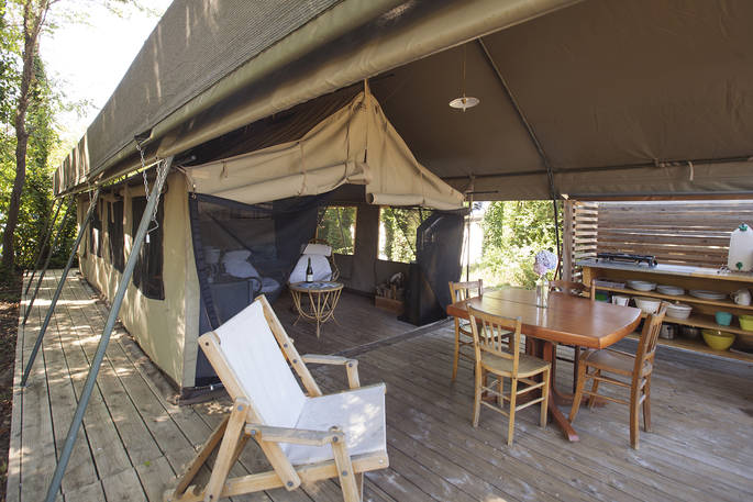 Sit at the dining table and relax outside of Penfret Lodge Tent at Bot-Conan Lodge Tent 