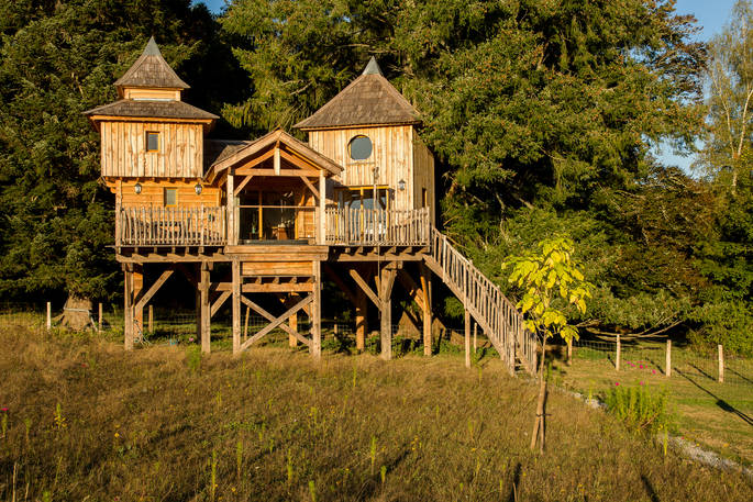 Sommet de Memanat treehouse exterior timber castle next to the trees with turret and terrace with sunken hot tub
