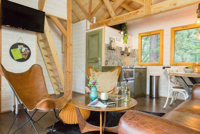 Sommet de Memanat treehouse interior open plan living area with ladder leading up to twin single beds in turret 